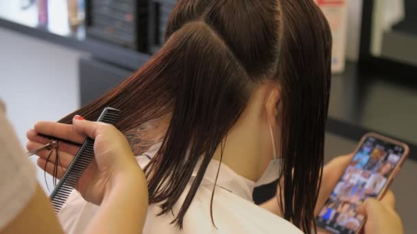 Tmavé vlasy žena sedí těší moderní sestřih v salonu — Stock video