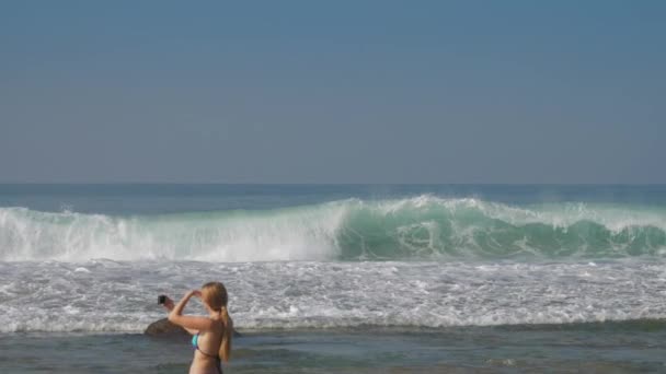 Mulher segura telefone nas mãos e tira fotos do oceano ondulando — Vídeo de Stock