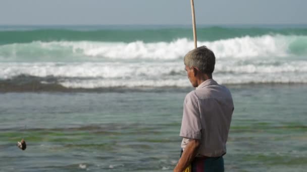 Pescador tiene caña de pescar en la mano y camina contra el océano — Vídeo de stock