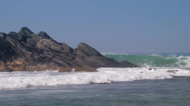 Onde oceaniche pesanti battono contro grandi pietre rocciose marrone scuro — Video Stock