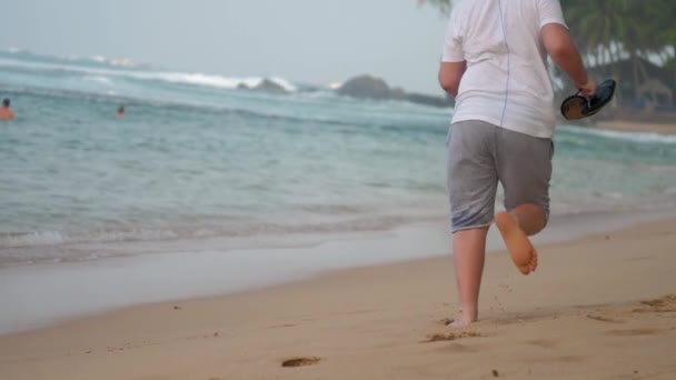 Ung man njuter av att springa längs tropiska havet strand — Stockvideo