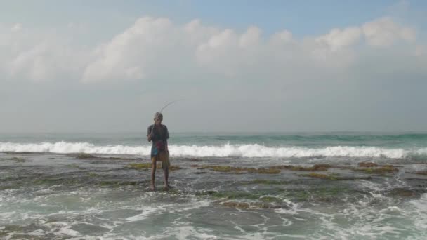W wieku Sinhalese człowiek z drewnianym wędką na oceanie powoli — Wideo stockowe