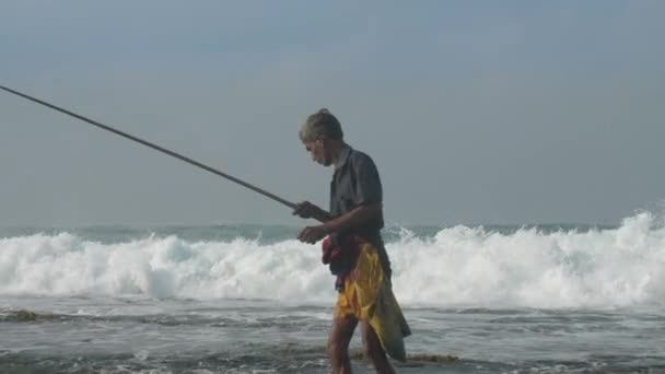 Gerijpte Sinhalese man met houten hengel aan oceaan langzaam — Stockvideo