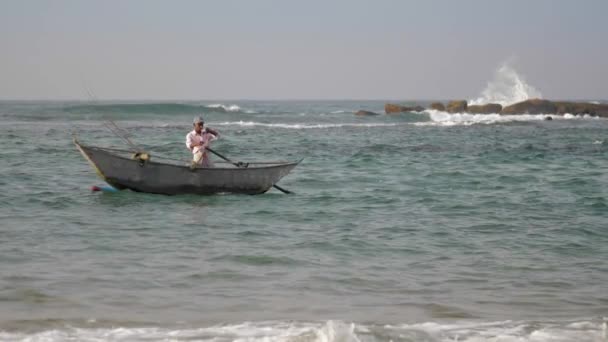 Homme se tient dans bateau fait à la main et navigue à travers la mer agitant — Video