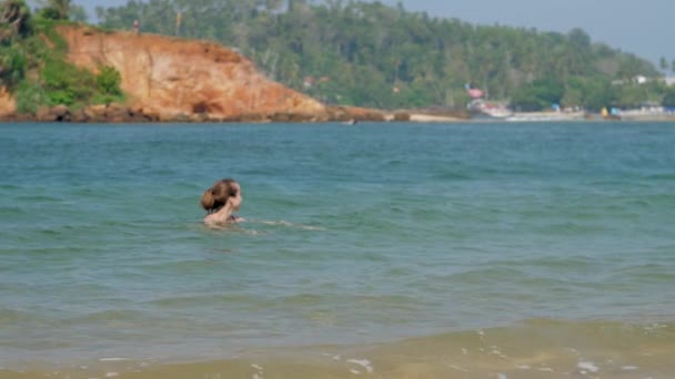 Femme avec un chignon à cheveux aime nager dans la mer tropicale lumineuse — Video