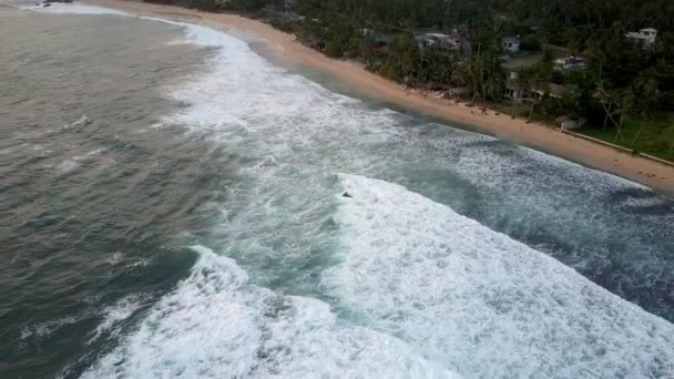 Вспенивающиеся океанские волны катятся по береговой линии с песчаными пляжами — стоковое видео