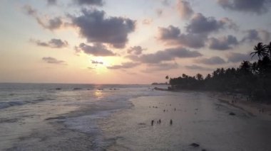 Turist siluetleri kıyı şeridi yakınlarında okyanus suyunda yüzerler.