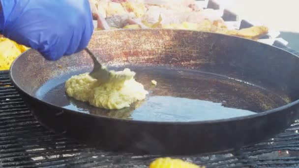 Kucharz stawia naleśniki ziemniaczane ciasto na czarnej patelni z łyżką — Wideo stockowe