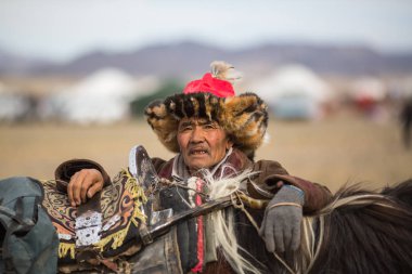 Olgiy, Moğolistan - Eyl 30, 2017: Kartal avcı kuşları Berkutchi Batı Moğolistan ile yıllık Ulusal yarışma sırasında kolunda altın kartal ile geleneksel kıyafetleri.