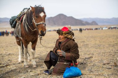 Olgiy, Moğolistan - Eyl 30, 2017: Kartal avcı kuşları Berkutchi Batı Moğolistan ile yıllık Ulusal yarışma sırasında kolunda altın kartal ile geleneksel kıyafetleri.