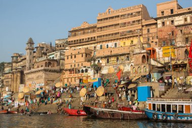 Varanasi, Hindistan - 26 Mar 2018: Bir tekne görünümünden suda Varanasi kıyı boyunca Ganj Nehri üzerinde süzülüyor. Efsaneye göre şehrin yaklaşık 5000 yıl önce Tanrı Shiva tarafından kuruldu.