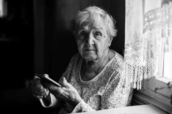 老年妇女手里坐着智能手机 — 图库照片