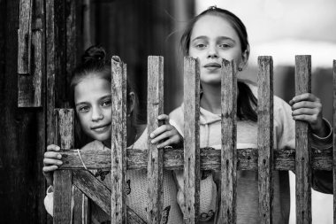 İki kız kardeş ya da kız açık havada köyde eğleniyor. Kameraya bakıyor. Siyah ve beyaz fotoğraf.