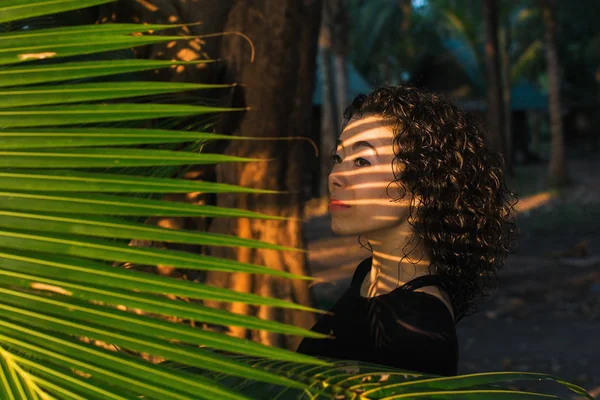 ヤシの木の葉の間で若い混血女性 — ストック写真