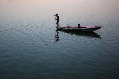 Varanasi, Hindistan - 26 Mar 2018: Bir teknede Boatmen Varanasi kıyı boyunca Ganj Nehri üzerinde suyun içinden süzülüyor. Efsaneye göre şehrin yaklaşık 5000 yıl önce Tanrı Shiva tarafından kuruldu