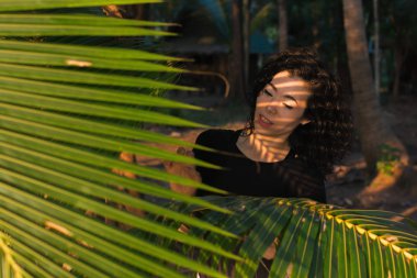 Genç karışık ırk kadın ve palmiye ağaçlarının yaprakları arasında.