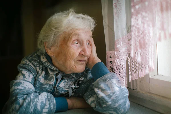 Bejaarde Vrouw Zitten Aan Tafel Kijkt Uit Het Raam — Stockfoto