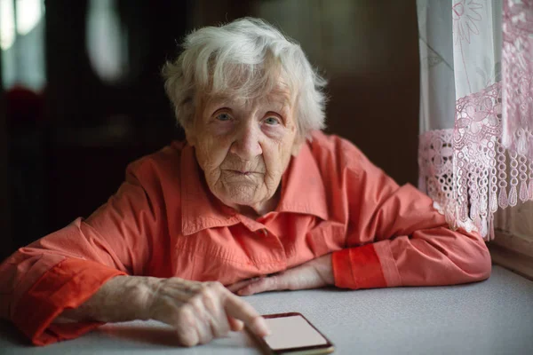 Old Woman Takes Smartphone Sitting Table House — Stock Photo, Image