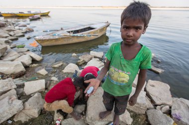 Varanasi, Hindistan - 13 Mar 2018: Yerel çocuk kazmak bir hediye olarak tanrılara hacı atılmış para bulmak için kutsal Ganj Nehri kıyılarındaki kum.