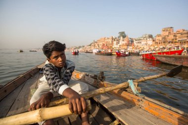 Varanasi, Hindistan - 26 Mar 2018: Bir teknede Boatmen Varanasi kıyı boyunca Ganj Nehri üzerinde suyun içinden süzülüyor. Efsaneye göre şehrin yaklaşık 5000 yıl önce Tanrı Shiva tarafından kuruldu.