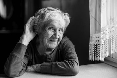 Bir işitme yaşlı kadın kulağı için elini koydu. Siyah ve beyaz fotoğraf.