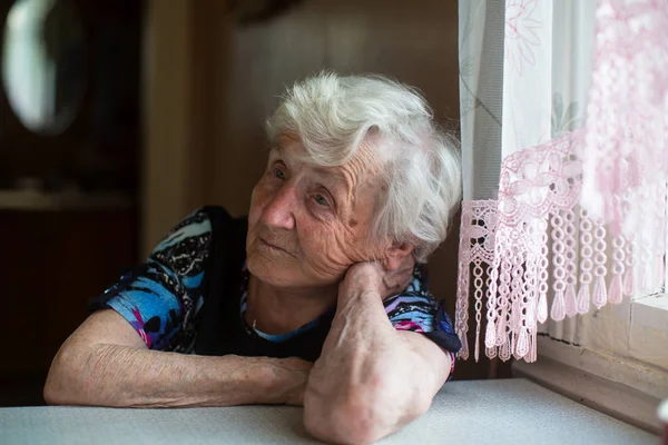 Yaşlı Bir Kadın Düşünceli Masada Oturur — Stok fotoğraf