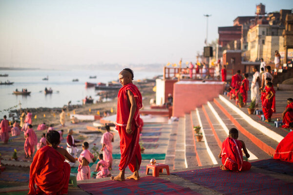 VARANASI, INDIA - MAR 18, 2018: Young hindu monks conduct a ceremony to meet the dawn on the banks of the Ganges, and raise the Indian flag. Varanasi is one of the 7 sacred cities of Hinduism. 