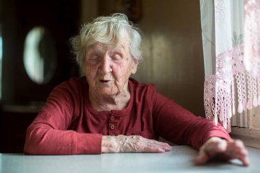 Rus yaşlı kadın evde bir masada oturan duygusal söz.