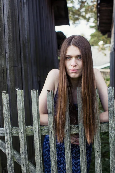 Uzun saçlı bir kız bir ahşap köy çit standları.