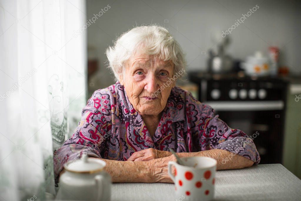 An elderly russian woman sitting at the kitchen table.