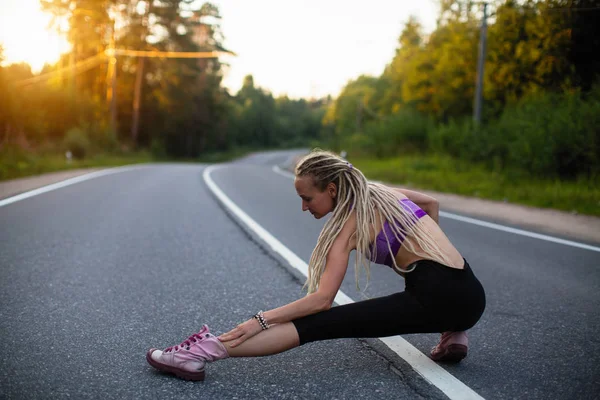 若い女性が道をジョギングする前にウォーム アップ — ストック写真