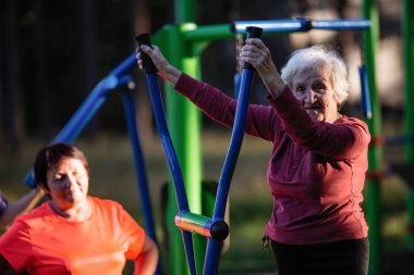 Yaşlı kadın parkta spor Bahçesi egzersizleri yapıyor.