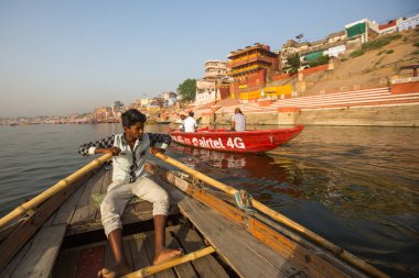 Varanasi, Hindistan - 26 Mar 2018: Bir teknede Boatmen Varanasi kıyı boyunca Ganj Nehri üzerinde suyun içinden süzülüyor. Efsaneye göre şehrin yaklaşık 5000 yıl önce Tanrı Shiva tarafından kuruldu.