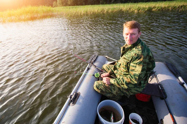 Fisherman catching fish on the river from rubber boat.