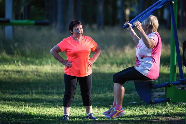 Koç ile simülatör egzersizleri yapıyor spor oyun üzerinde yaşlı kadın.