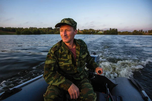 Fisherman on rubber motor boat floats on the lake.