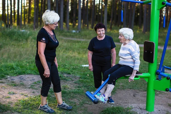 Oudere Vrouw Een Sport Simulator Twee Vrouwen Helpen Haar Oefeningen — Stockfoto