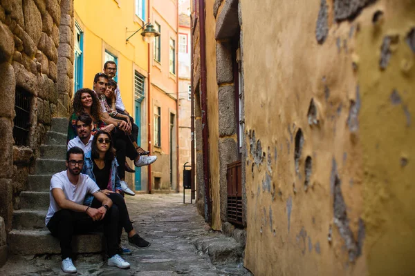 在葡萄牙波尔图狭窄的街道上坐着的年轻人公司 — 图库照片