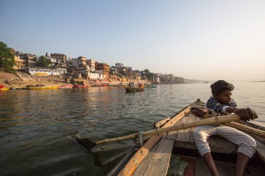 Varanasi, Hindistan - 26 Mar 2018: Bir teknede Boatmen Varanasi kıyı boyunca Ganj Nehri üzerinde suyun içinden süzülüyor. Efsaneye göre şehrin yaklaşık 5000 yıl önce Tanrı Shiva tarafından kuruldu.