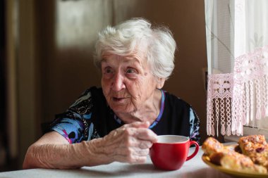 Yaşlı bir kadın evde oturup kahvaltı vardır.