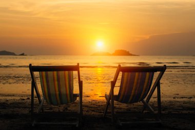 Gün batımı sırasında deniz sahilde şezlong.