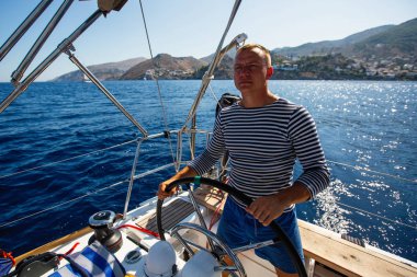 Genç adam bir yelkenli tekne dümen tekne.