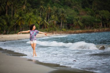 Deniz sahilde yürüyen genç karışık ırk kadın.