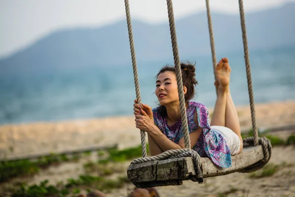 年轻的混血女子躺在海边的秋千上 — 图库照片