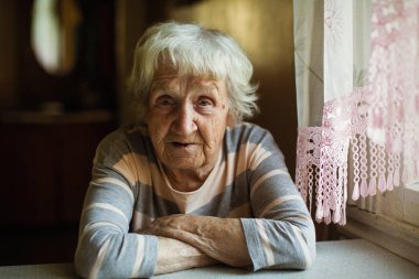 Yaşlı bir kadın ne yazık ki pencerenin oturur.