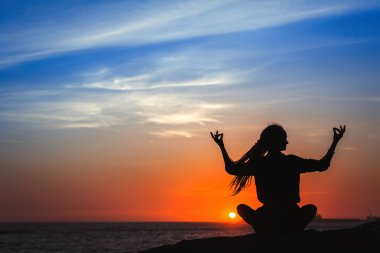 Yoga kadın siluet serisi. Muhteşem gün batımı sırasında okyanus üzerinde meditasyon. 