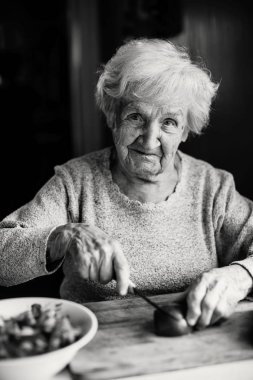 Yaşlı kadın sebze salata için hazırlanıyor. Siyah ve beyaz fotoğraf.