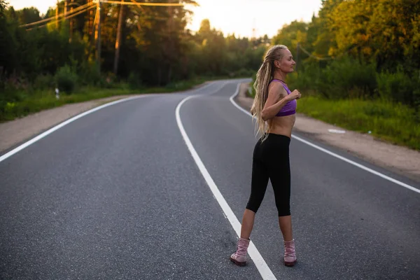 走っている女性は郊外の道でジョギングする前にウォーム アップ — ストック写真