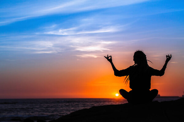 Yoga silhouette meditation girl on the sea during sunset.