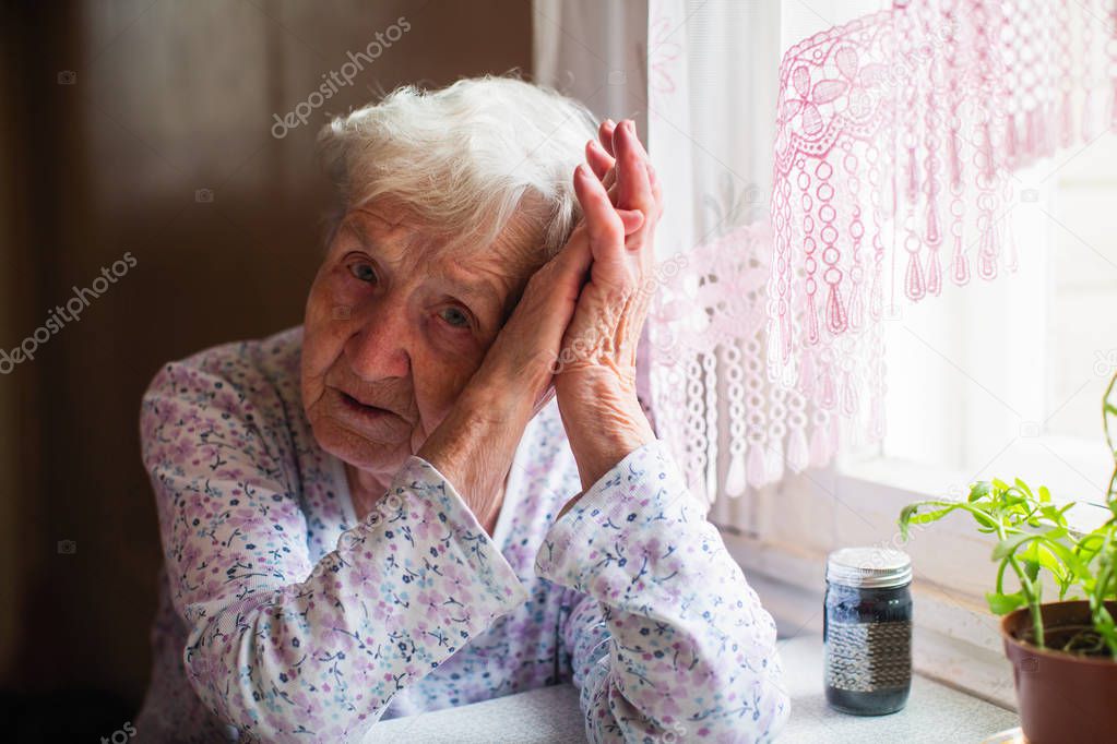 Sad elderly woman sitting in her home. 